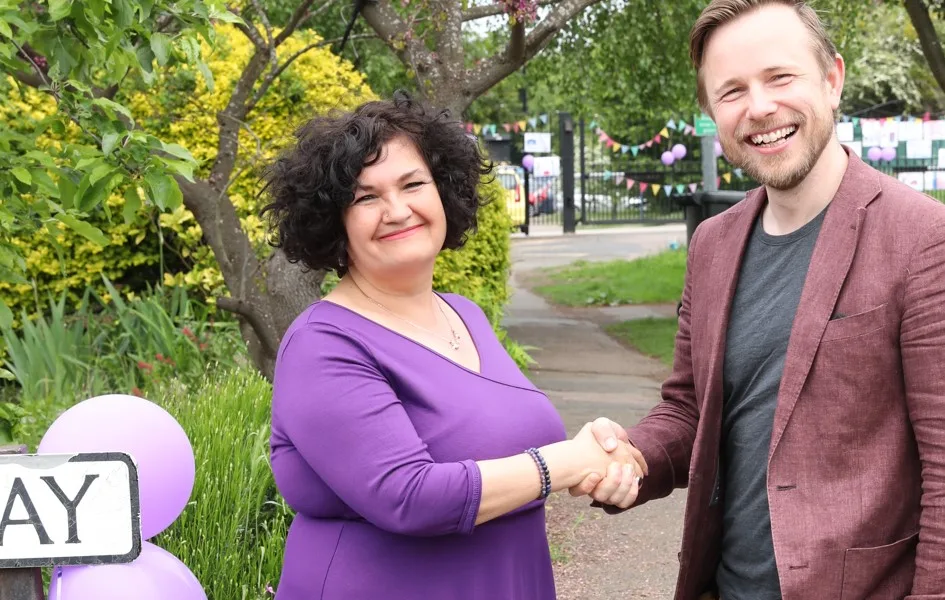 Headteacher Rachel Snape with Cllr Alex Beckett on problematic junction outside the school, posters in the background.