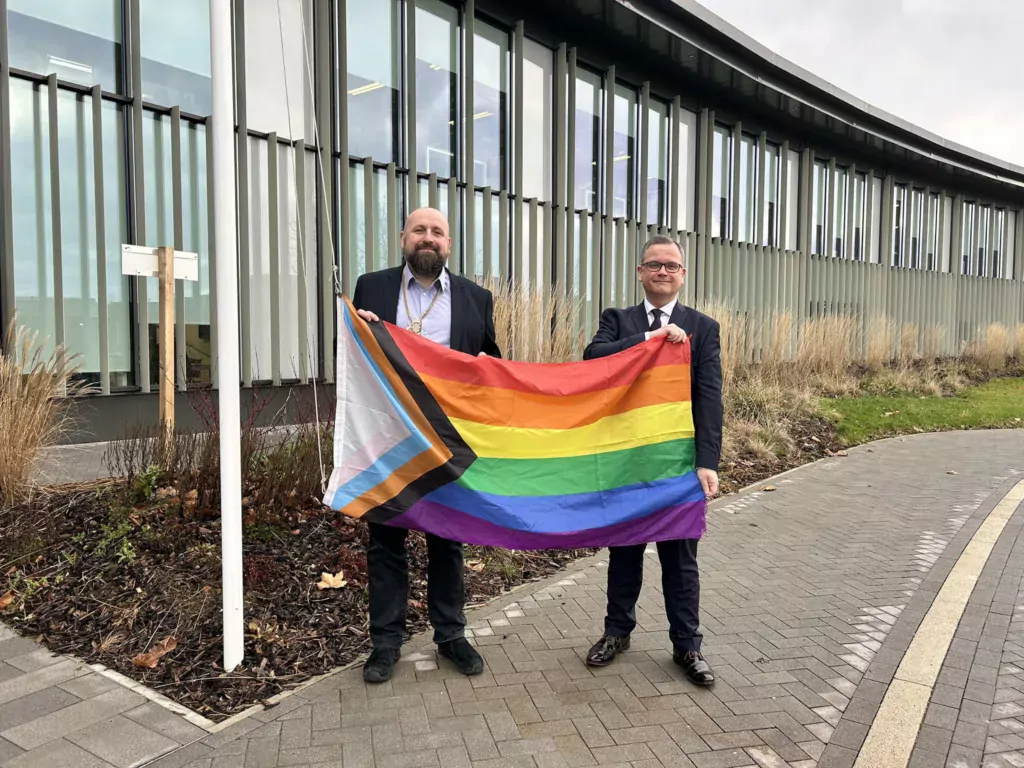 February 2023: Cambridgeshire Council Chief Executive Stephen Moir flying the Pride Flag over New Shire Hall in support of LGBT+ History Month. He is pictured with Cllr Stephen Ferguson (left), at the time chair of the county council.