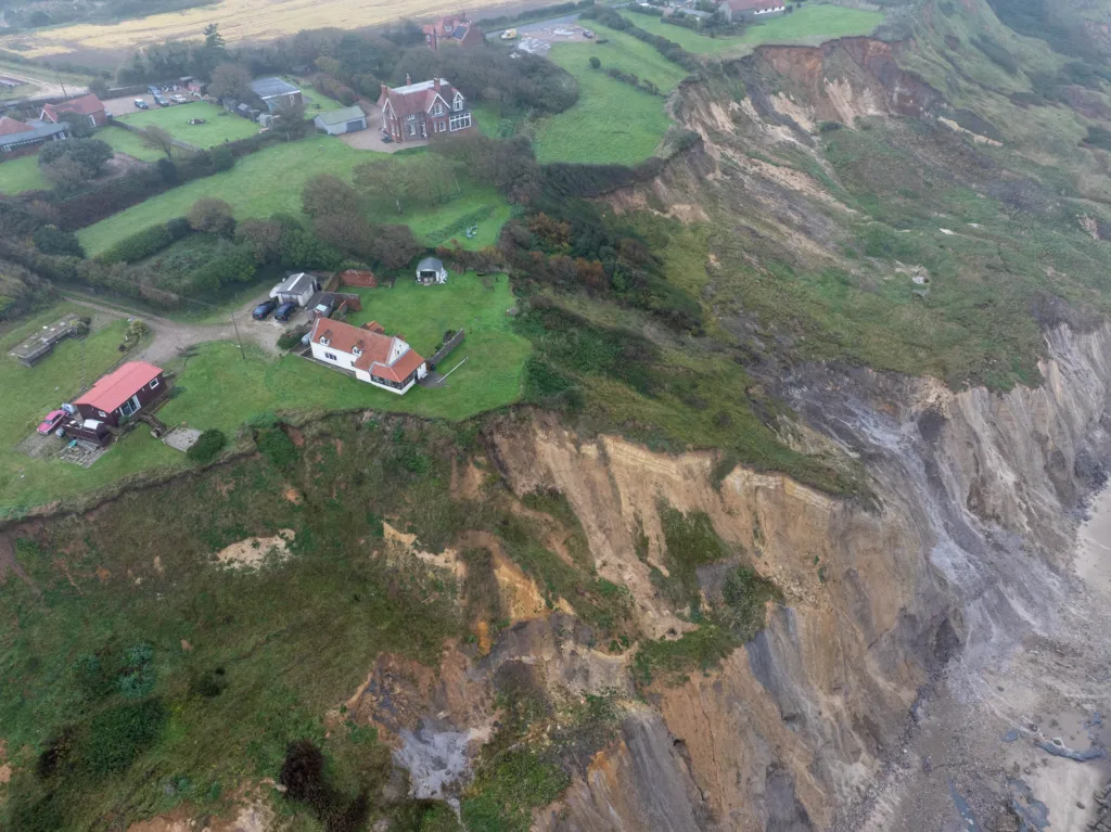 Shocking photos taken today (Thurs) show a three-bedroom house hanging perilously over a cliff edge on the north Norfolk coast after a surge of recent cliff falls. Trimingham Thursday 04 April 2024 Picture by Terry Harris
