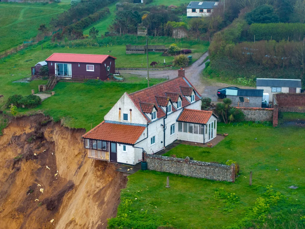 Shocking photos taken today (Thurs) show a three-bedroom house hanging perilously over a cliff edge on the north Norfolk coast after a surge of recent cliff falls. Trimingham Thursday 04 April 2024 Picture by Terry Harris
