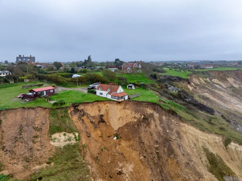 Shocking photos taken today (Thurs) show a three-bedroom house hanging perilously over a cliff edge on the north Norfolk coast after a surge of recent cliff falls., Trimingham, Norwich Thursday 04 April 2024. Picture by Terry Harris