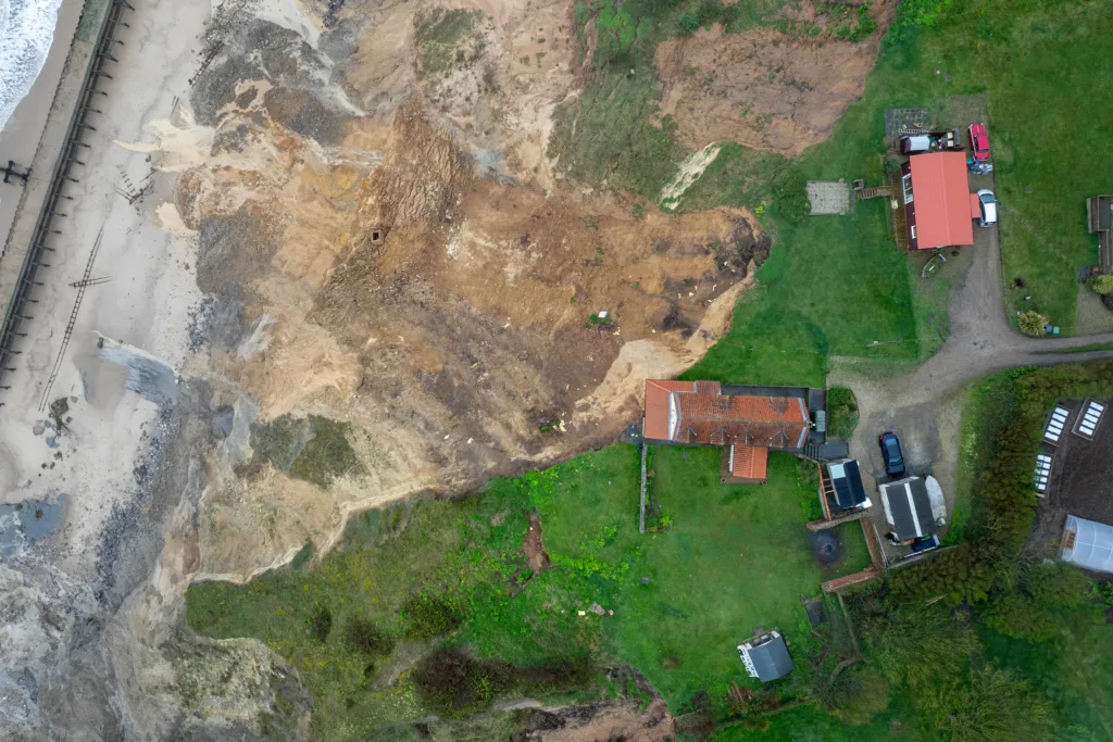 Shocking photos taken today (Thurs) show a three-bedroom house hanging perilously over a cliff edge on the north Norfolk coast after a surge of recent cliff falls. Trimingham Thursday 04 April 2024 Picture by Terry Harris