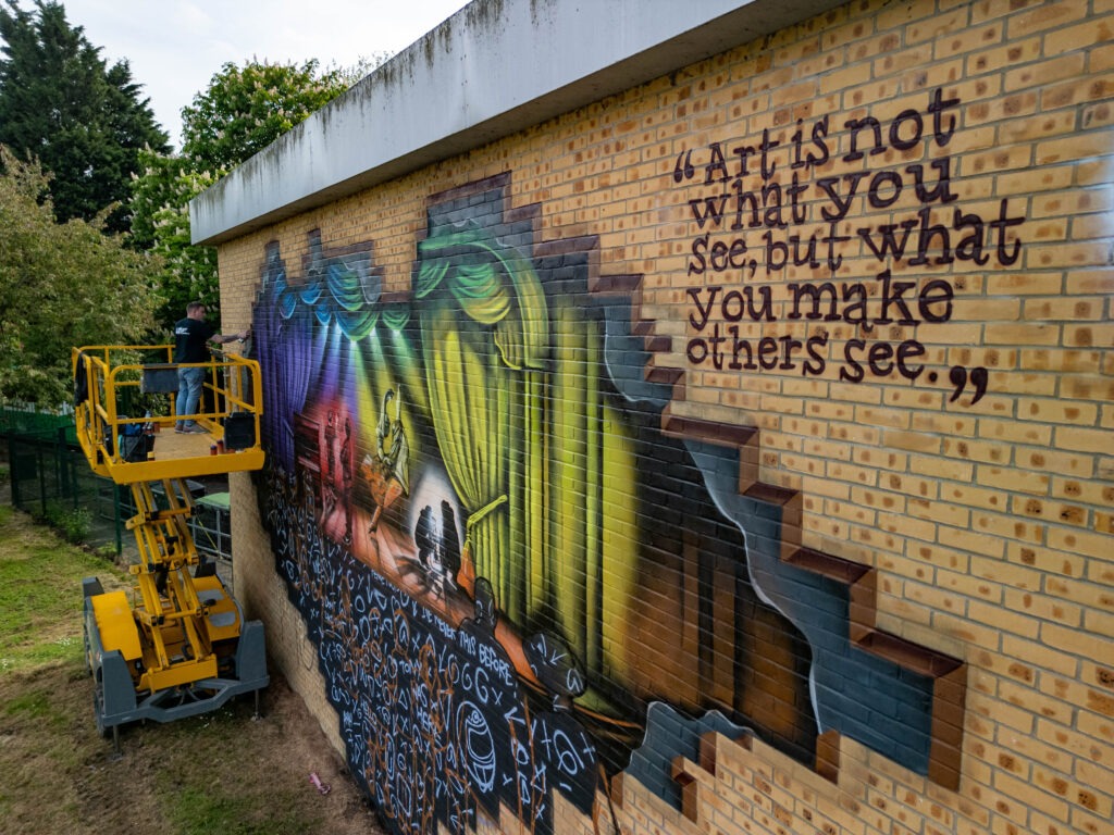 Nathan Murdoch working on a mural on the wall of the Key Theatre, Peterborough.  Embankment, PeterboroughWednesday 08 May 2024. Picture by Terry Harris.