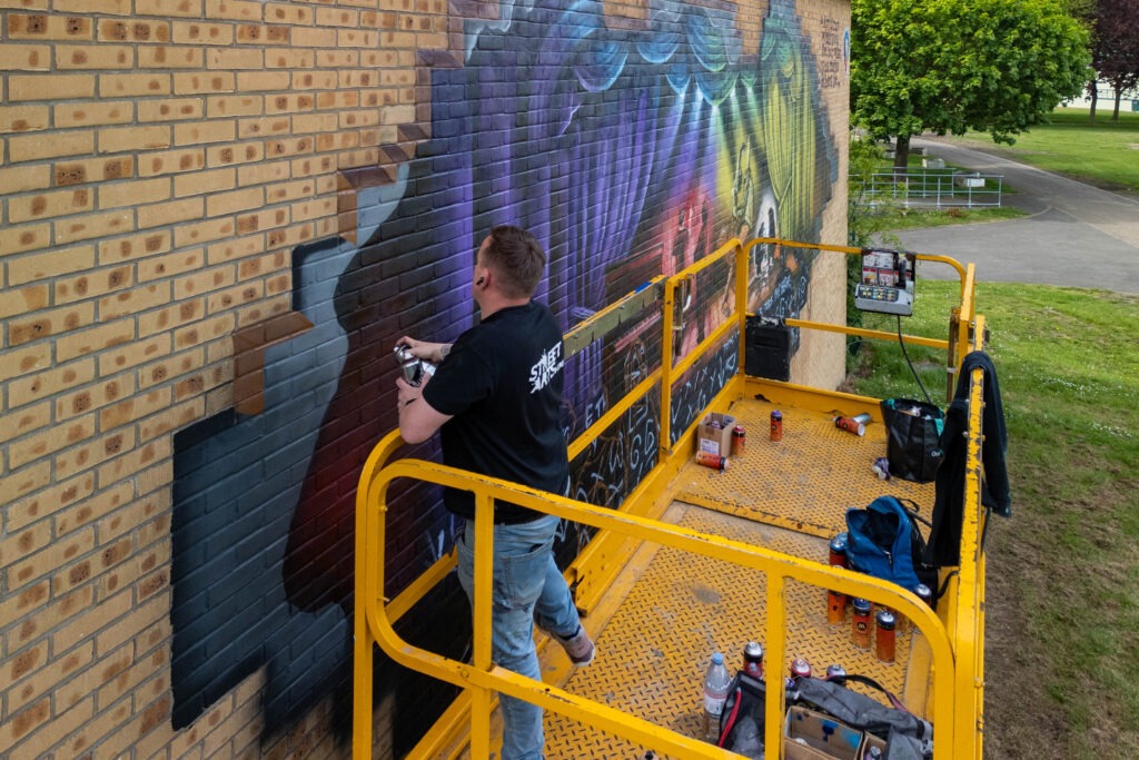 Nathan Murdoch working on a mural on the wall of the Key Theatre, Peterborough.  Embankment, PeterboroughWednesday 08 May 2024. Picture by Terry Harris.