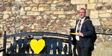Mayor of Huntingdon Cllr Karl Brockett tying a ribbon around the bench